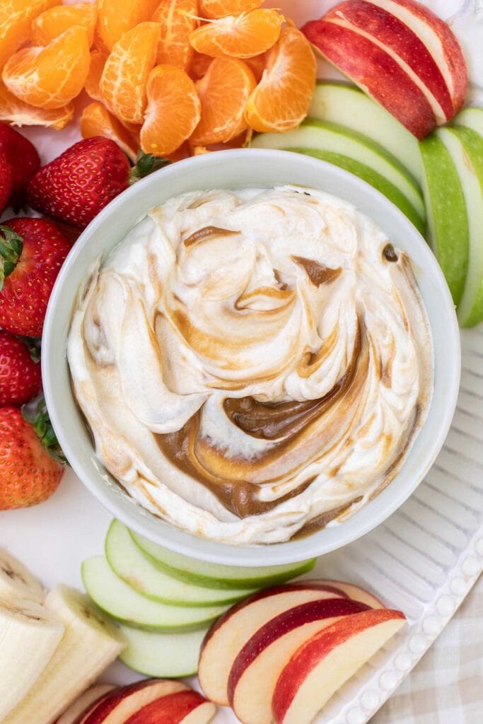 A platter of fruit with a big bowl of Greek yogurt fruit dip in the center.