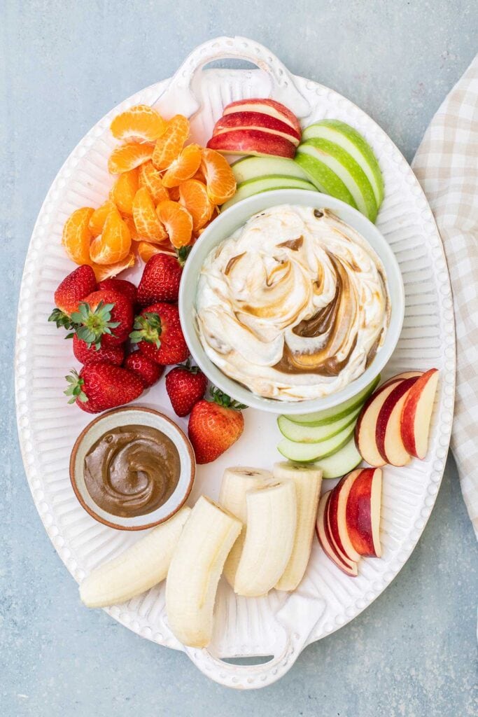A platter of apples, mandarins, strawberries, and bananas, with a Greek yogurt dip.