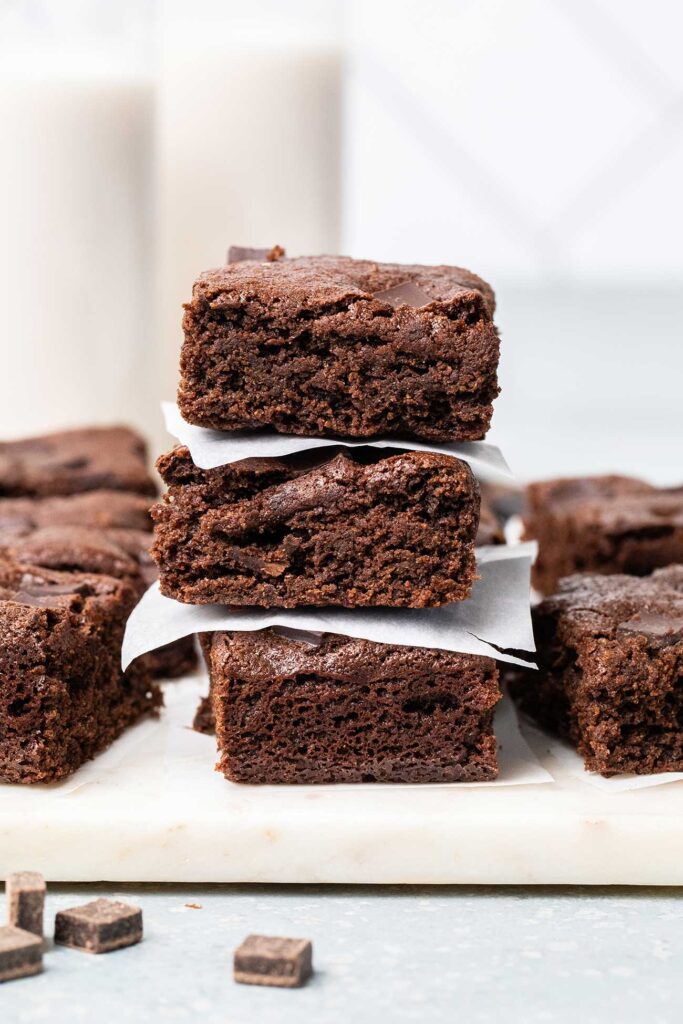 A stack of 3 almond flour brownies in front of a glass of milk.