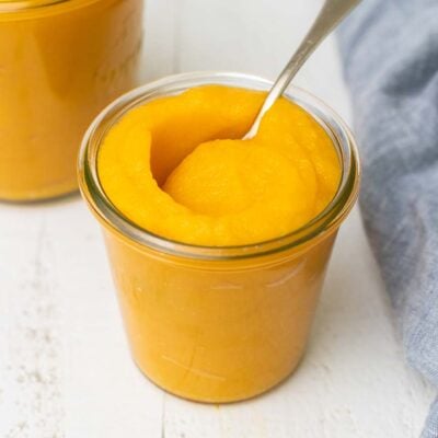 A jar filled with pumpkin puree with a spoon sticking out of the top.