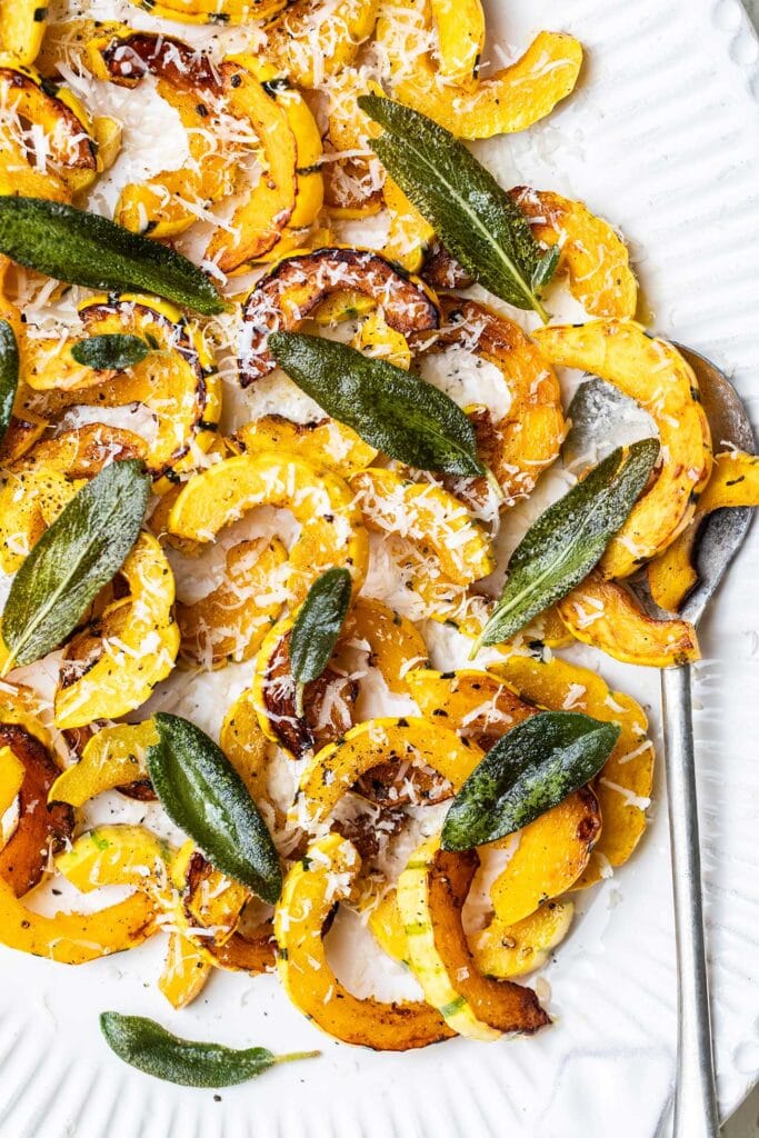 A platter of sauteed delicata squash topped with grated parmesan and fried sage.