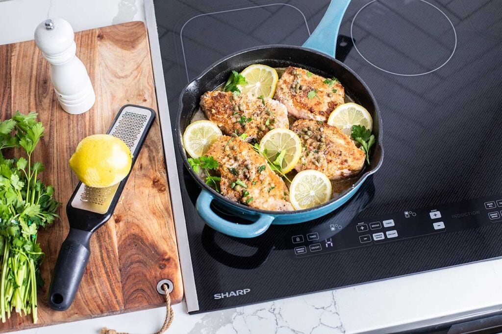 A cast iron skillet on a Sharp Oven with pork piccata.