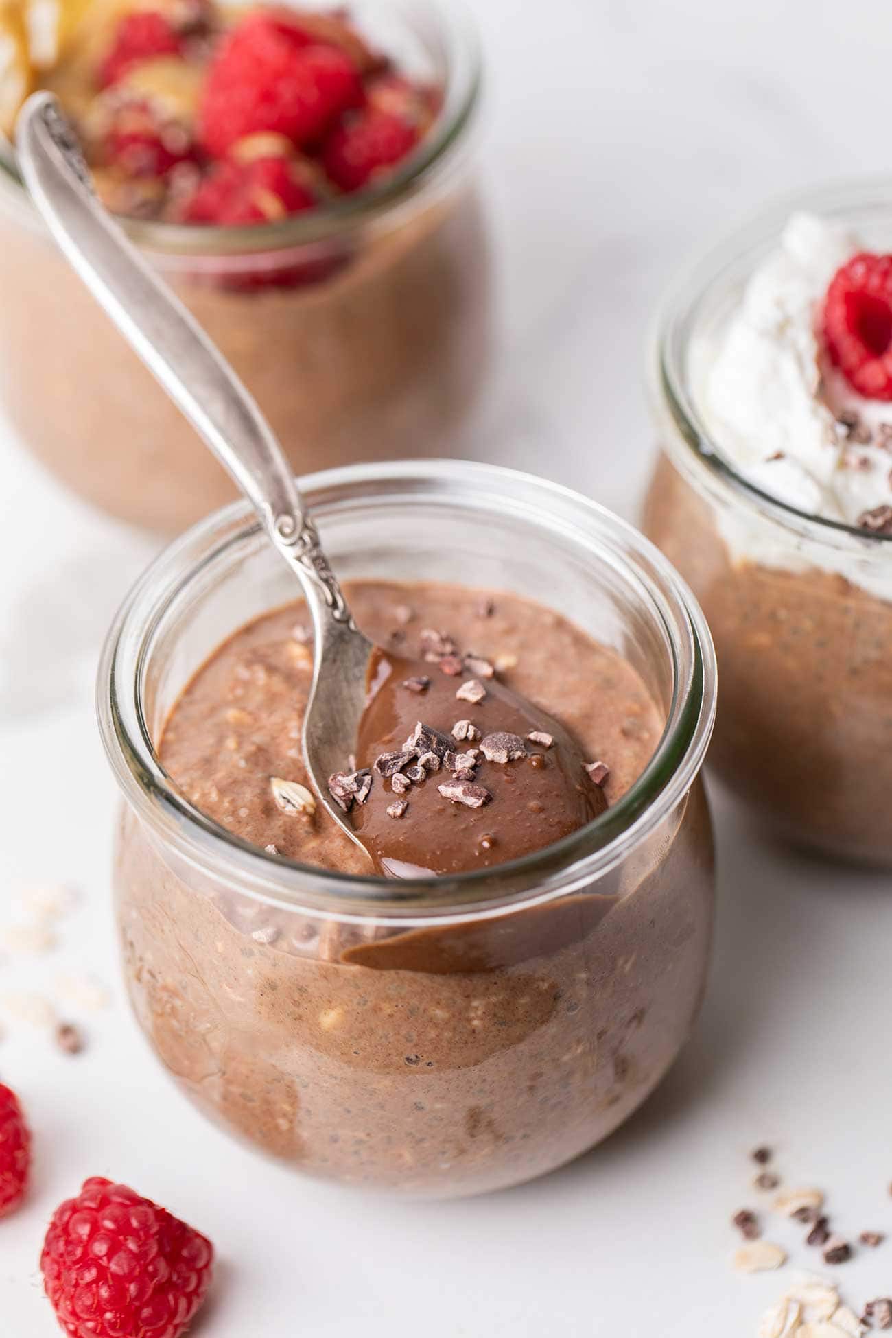 Jars of chocolate overnight oats shown with toppings.
