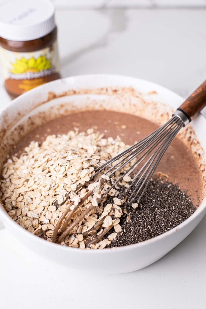 A bowl of a chocolate mixture shown with oats and chia seeds added in.