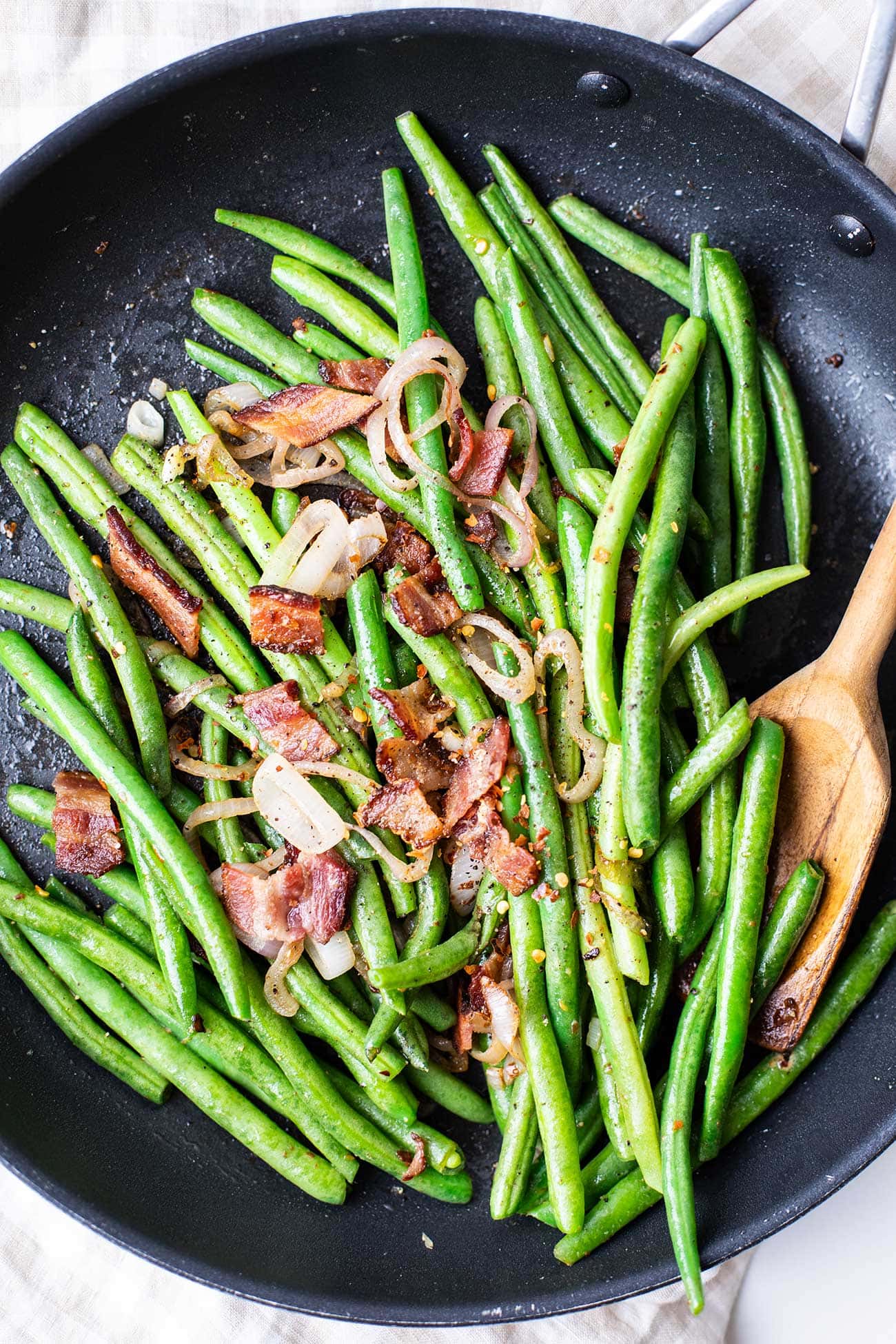 Vibrantly colored green beans sauteed and topped with crunchy bites of bacon.