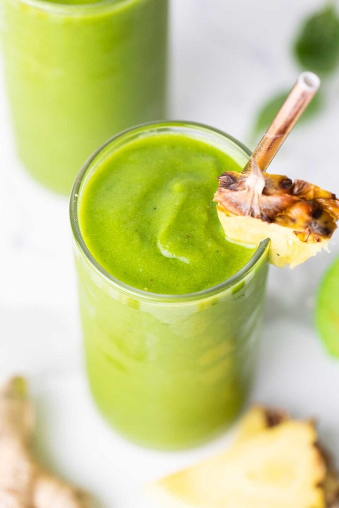 A top down look at a vibrant green smoothie garnished with a pineapple wedge.