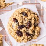 A close up look at an oatmeal raisin cookie sitting on a cooling rack.