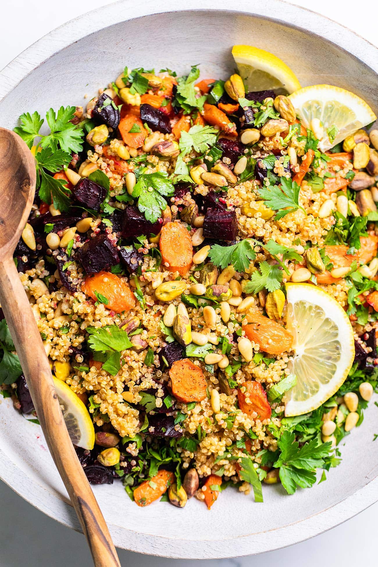 A close up look at a beet quinoa salad with roasted carrots topped with pistachios and pine nuts.