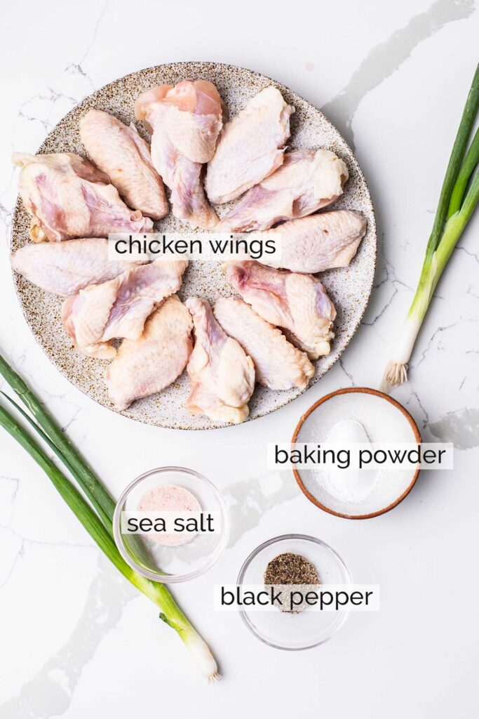 A plate of raw chicken wings shown with baking powder and seasonings.