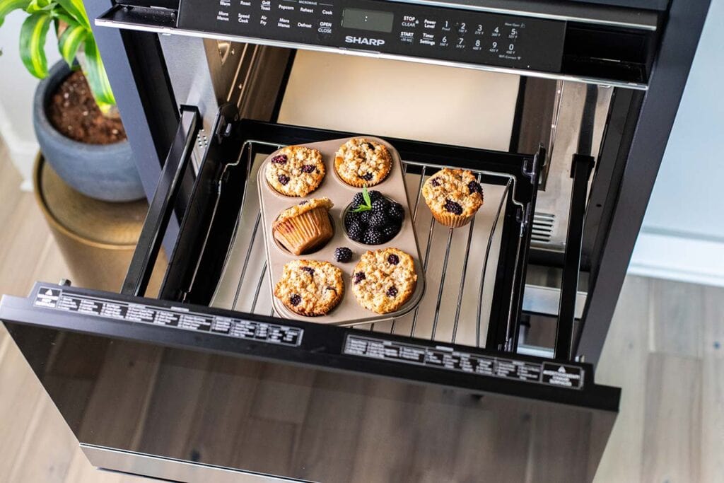 A muffin pan with 6 healthy blackberry muffins sitting in the Sharp Microwave Convection Oven.