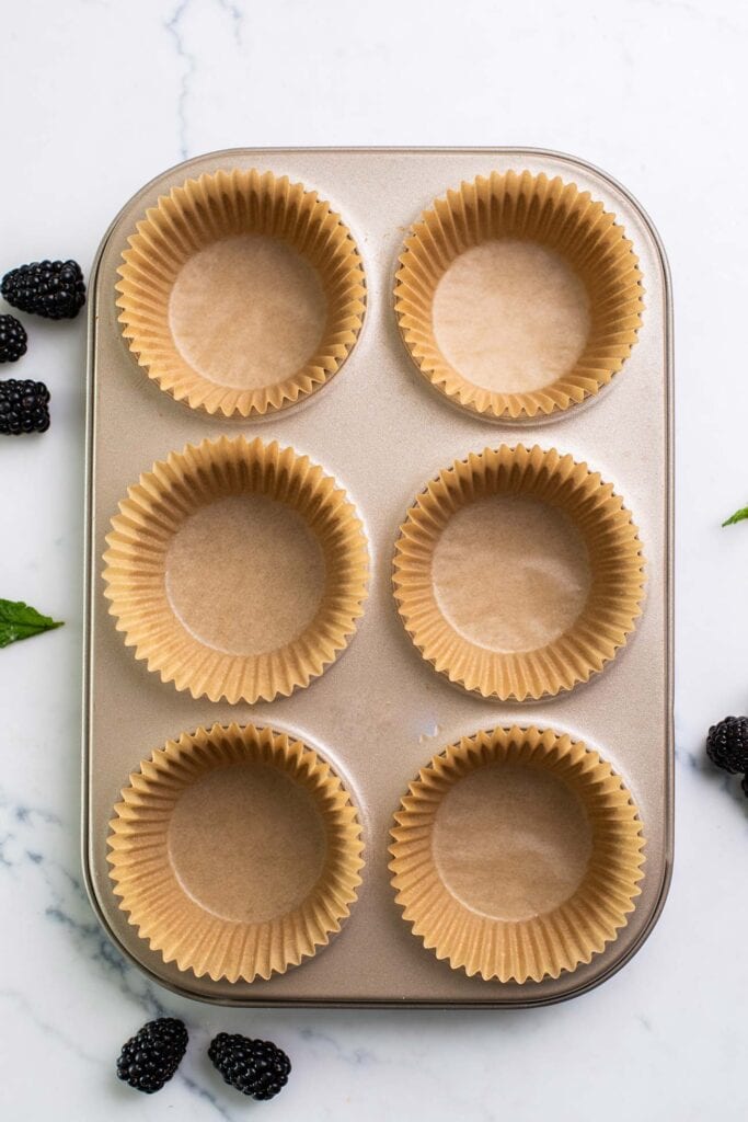 A muffin tin shown lined with papers.