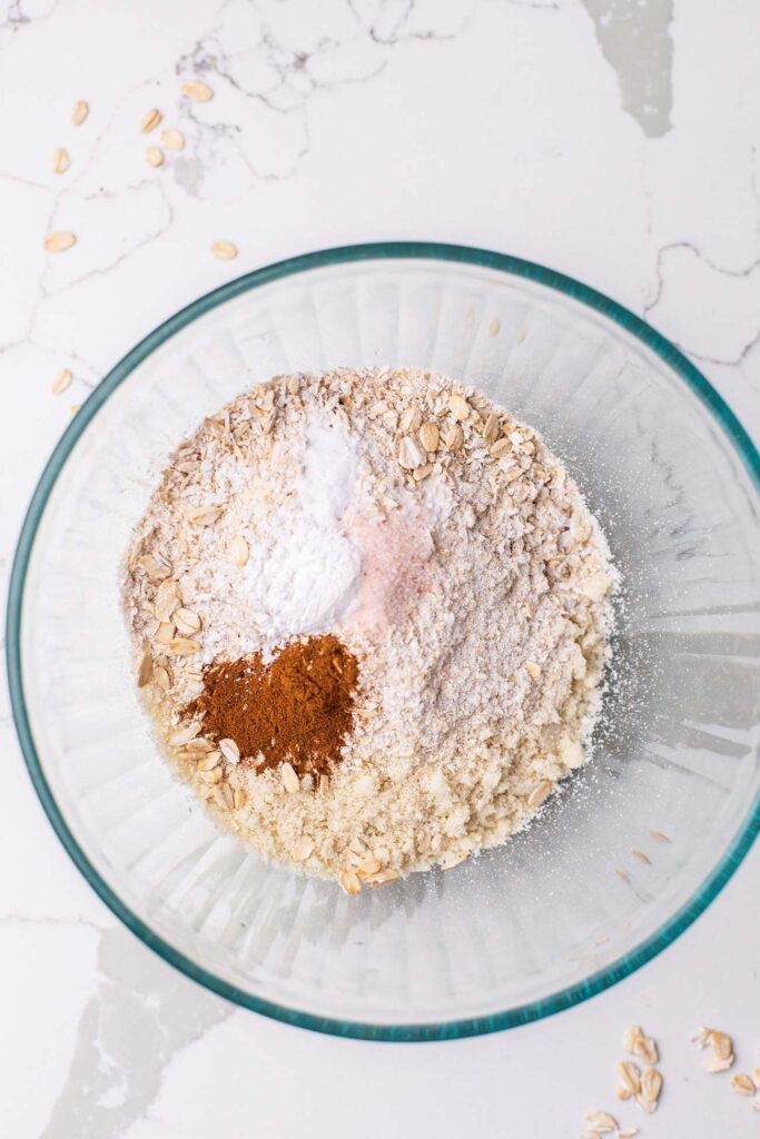 A bowl with ground oats, almond flour, baking powder and cinnamon.