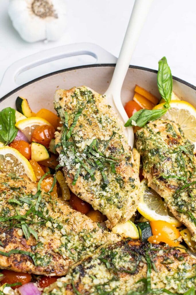 A spatula removing a pesto chicken breast from a skillet.