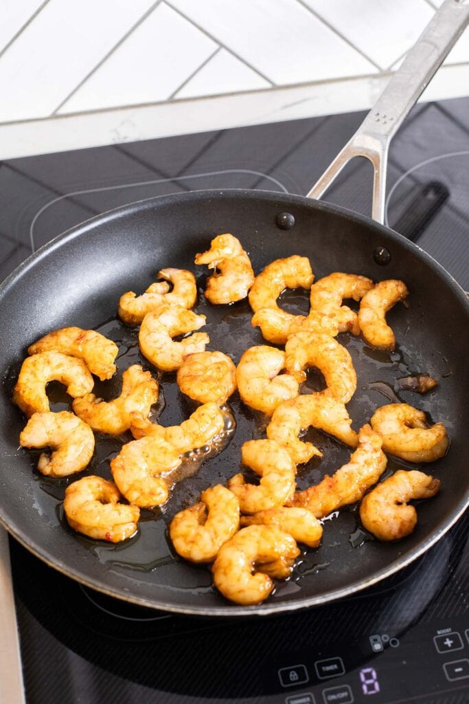 Thai marinated shrimp shown cooking in a skillet.