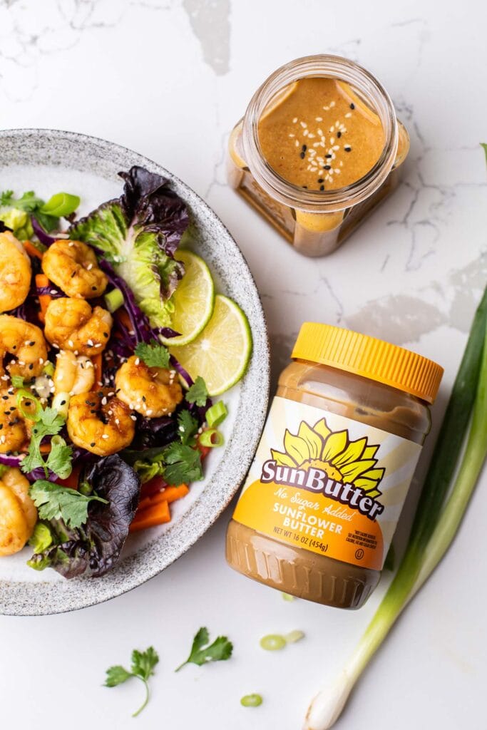 A jar of SunButter sitting next to a Thai Shrimp Salad.