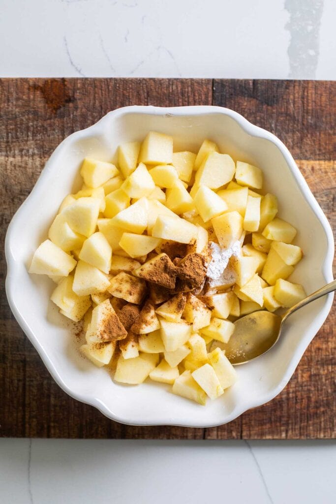 Apples being mixed with cinnamon, arrowroot, salt, honey, and coconut oil.