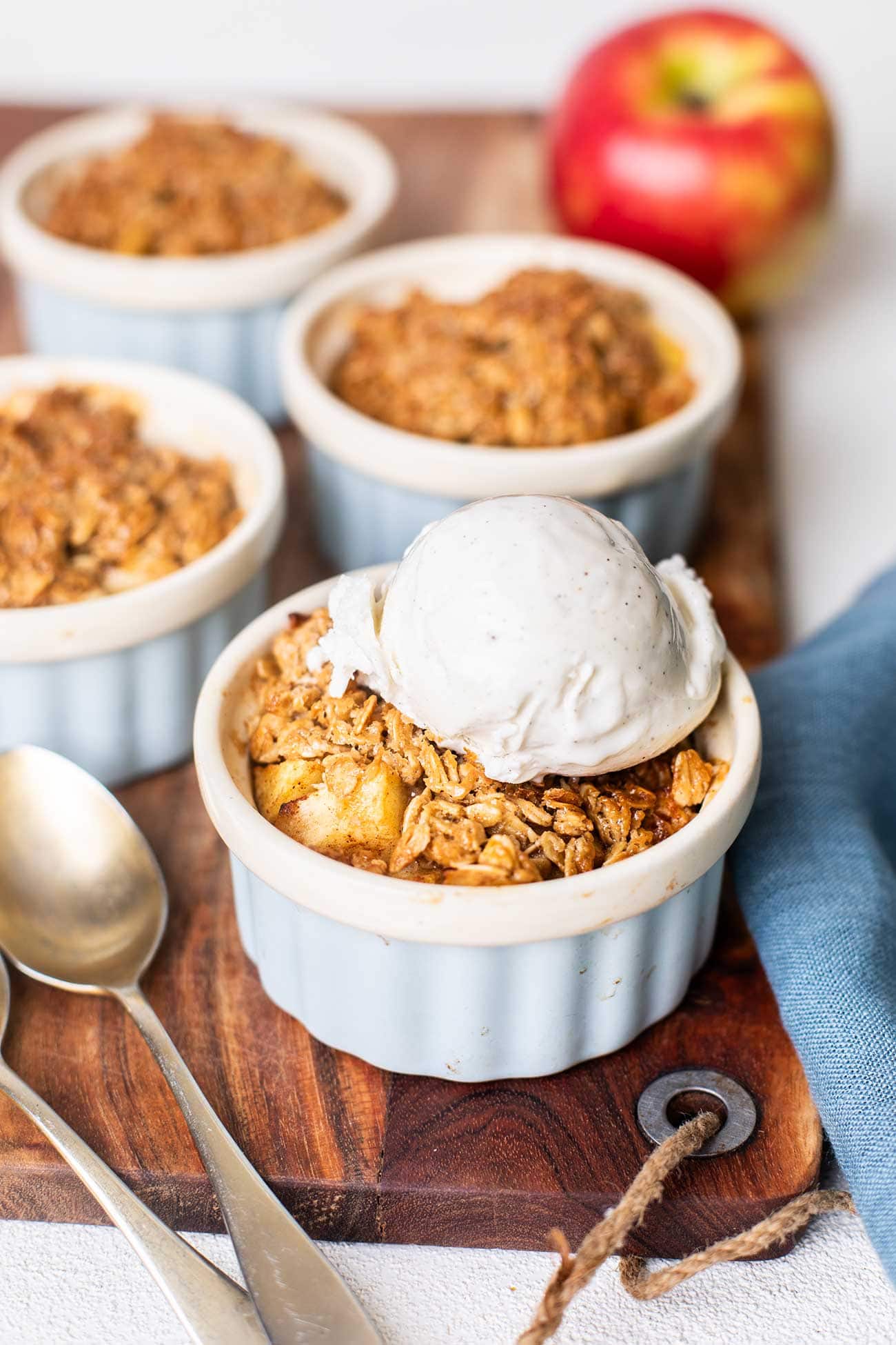 4 individual servings of apple crisp topped with vanilla ice cream.