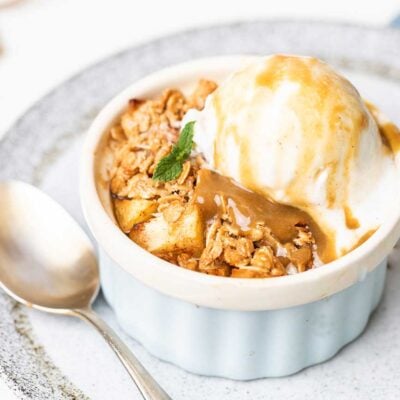 An apple crisp topped with ice cream and caramel sauce.