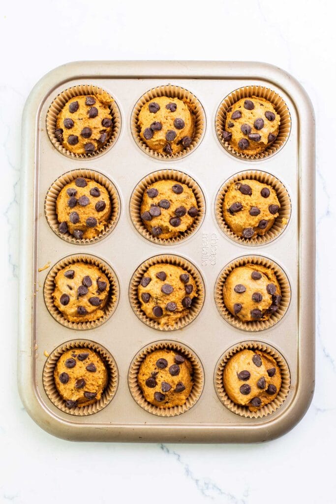 Batter divided into the 12 cavities in the muffin tin.