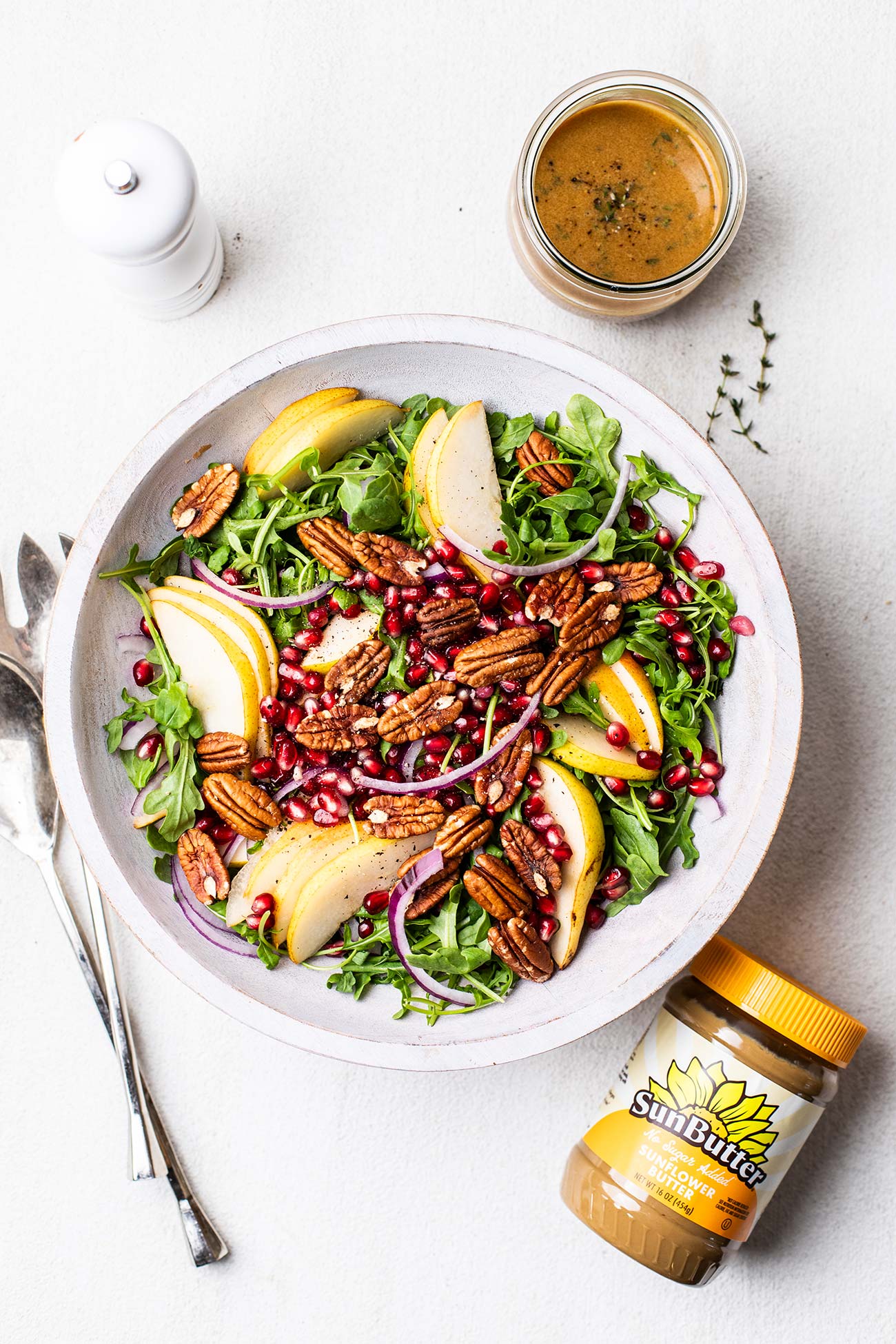 A pear and arugula salad next to a jar of SunButter.