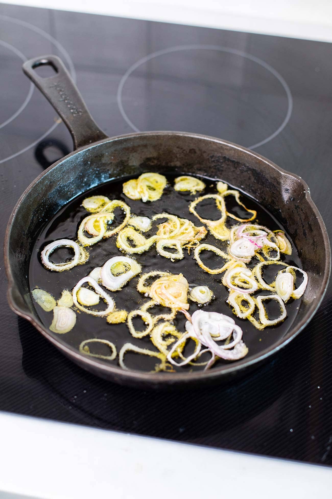 Shallots frying in a skillet with avocado oil.