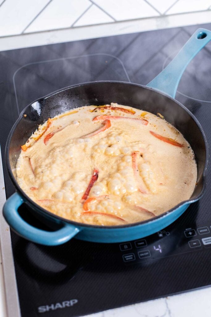 A creamy coconut sauce simmering in a skillet.