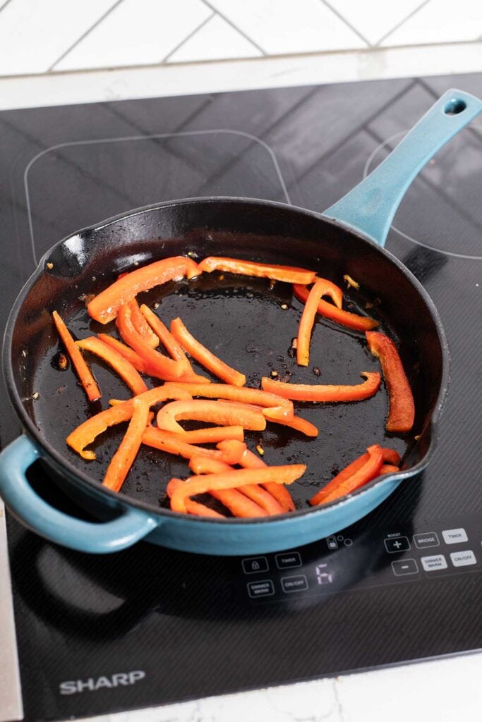 Red peppers sauteed in a skillet.