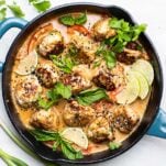 A skillet shown with Thai chicken meatballs in a creamy coconut sauce.