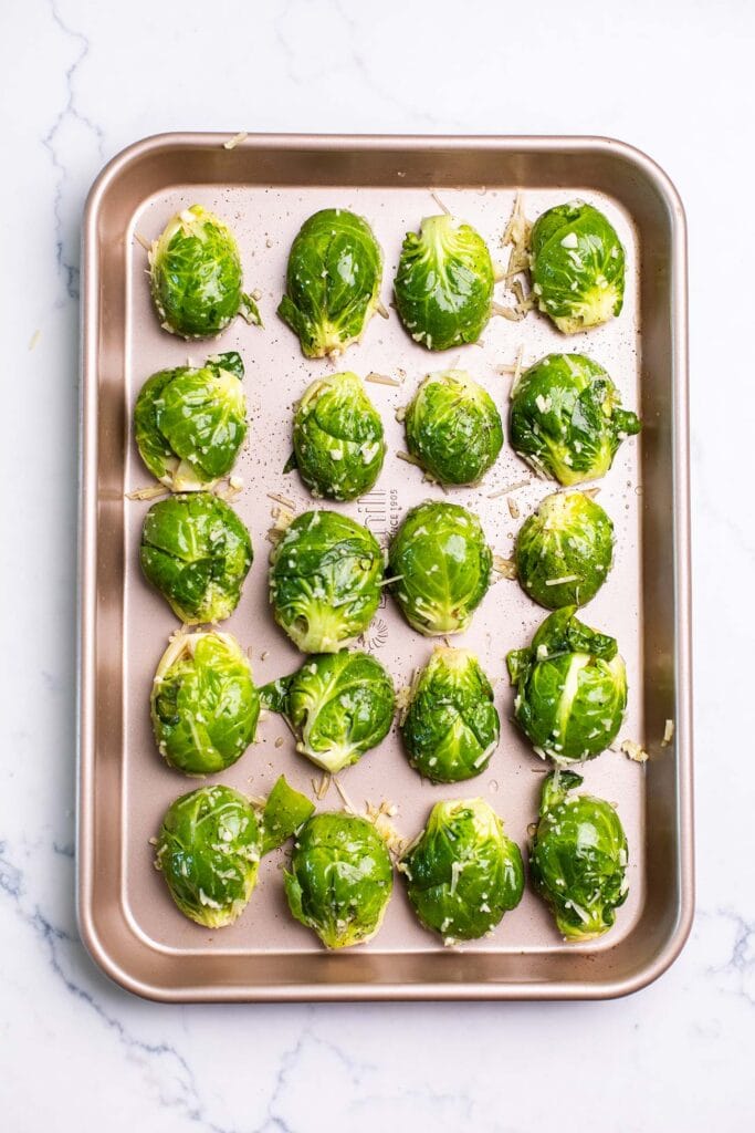 Brussels sprouts shown lined up on a baking tray with space between each one.