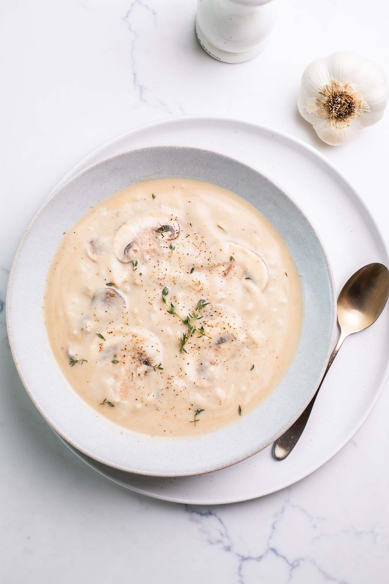 A bowl of dairy free cream of mushroom soup shown garnished with thyme.