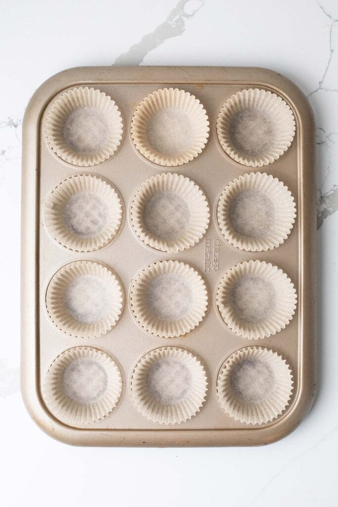 A muffin tin shown lined with muffin papers.