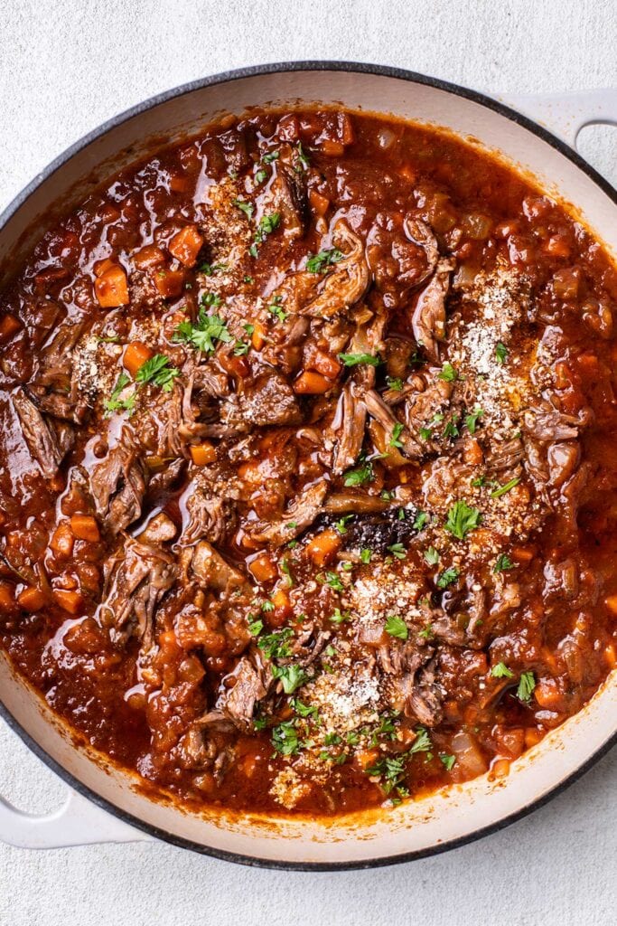 The meat stirred back into the braising liquid to form a ragu sauce.