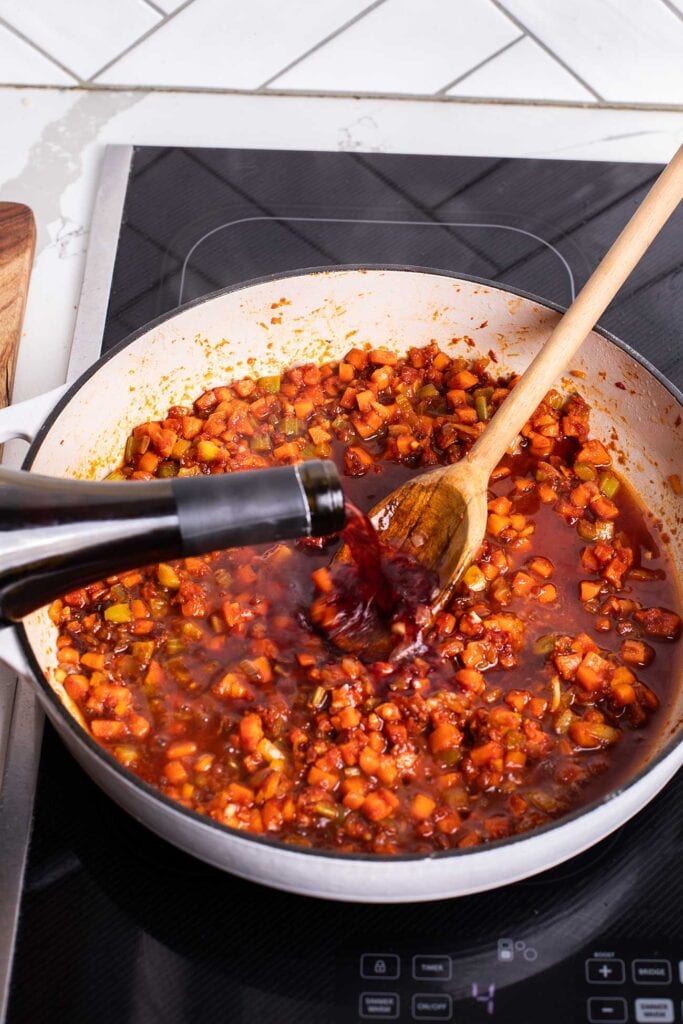 Wine being poured in to the pan, deglazing the browned bits left behind by the vegetables.