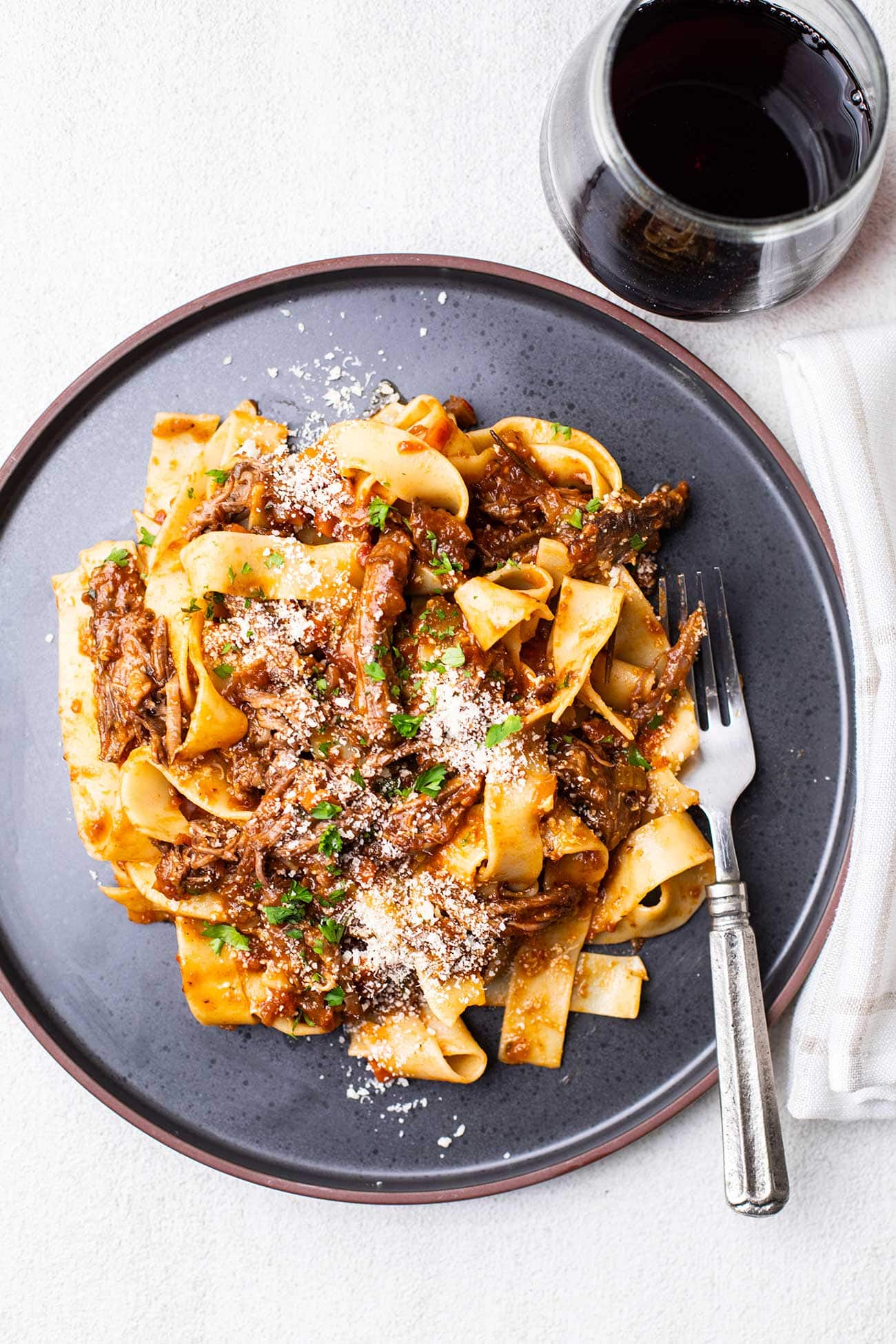 A plate with beef short rib ragu served on top of pappardelle pasta.