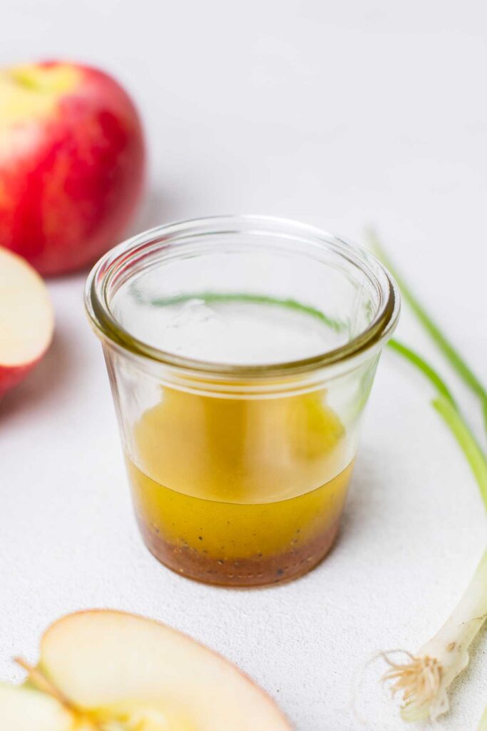 An apple cider vinaigrette dressing shown in a glass jar.