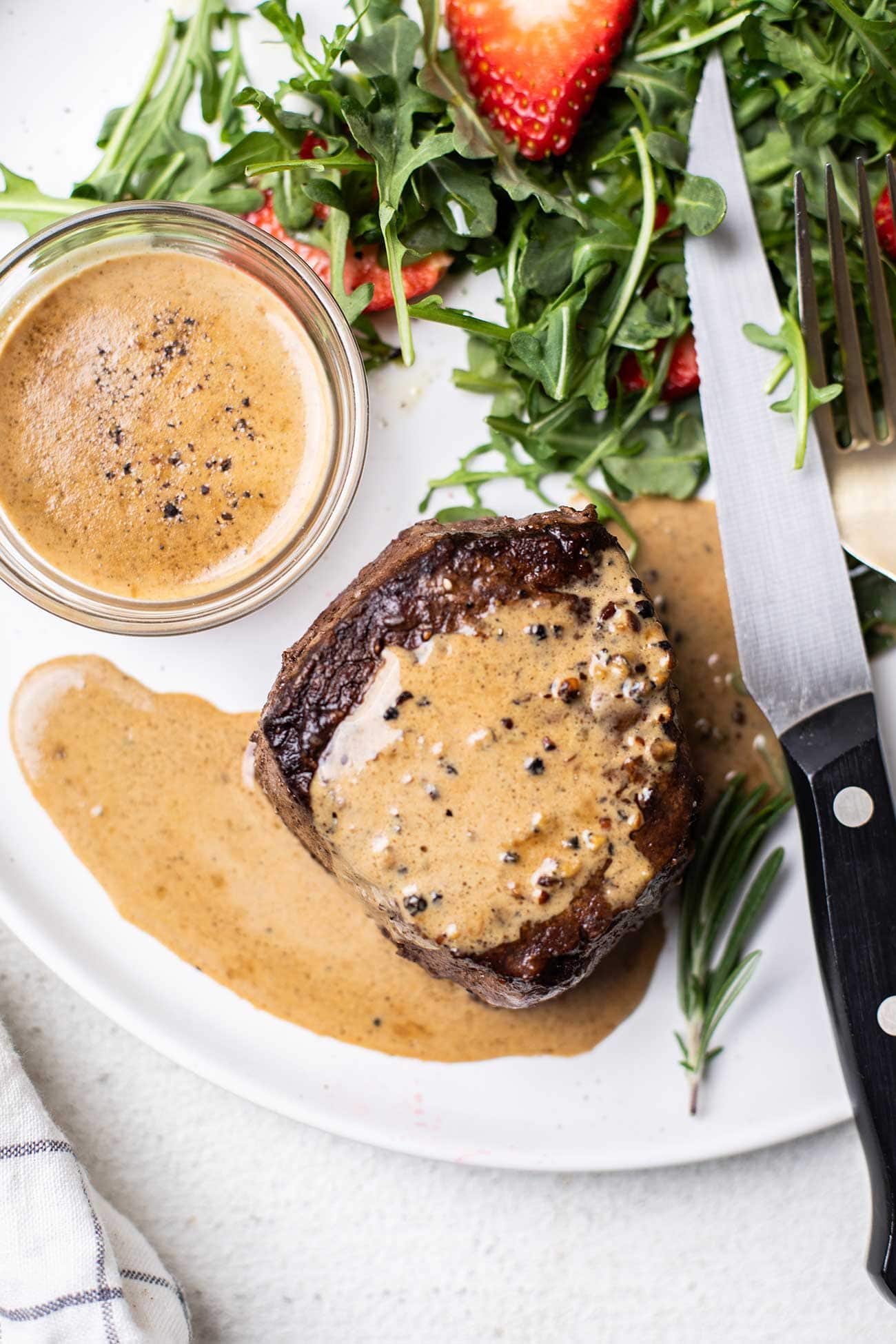 A creamy peppercorn sauce shown drizzled over a filet mignon steak.