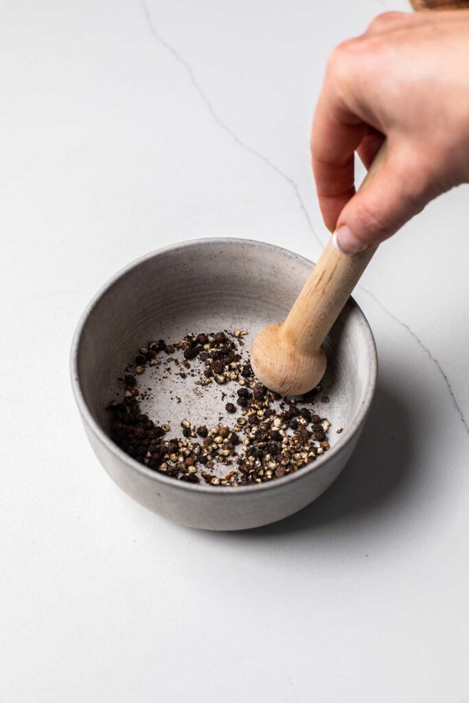 Peppercorns in a bowl being crushed.