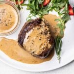 A creamy peppercorn sauce shown serve on top of a filet mignon steak.