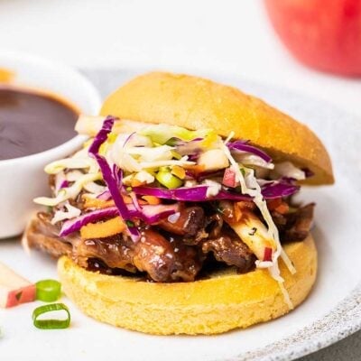 A close up look at shredded pork coated in a honey bbq sauce on a brioche bun.