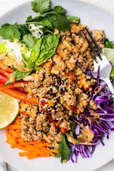 A colorful spring roll salad topped with spicy ginger chicken.