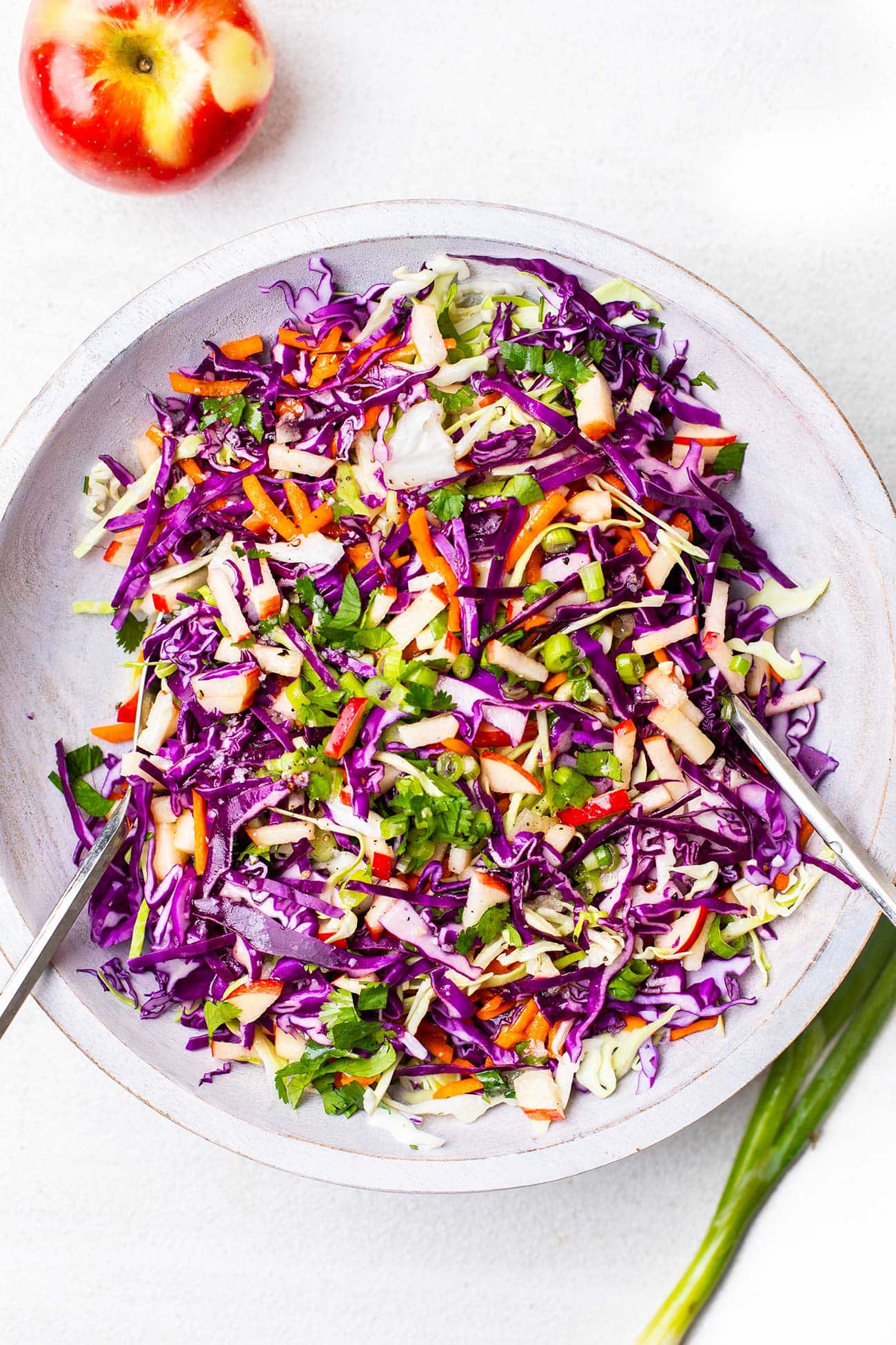 A crunchy apple slaw shown garnished with cilantro and green onions.