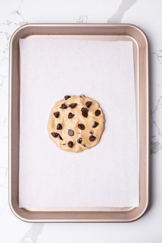 Cookie dough pressed into a cookie shape on a baking sheet.