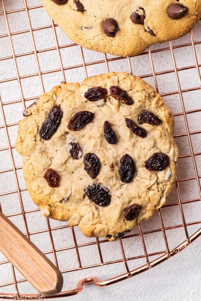 An oatmeal raisin protein cookie on a cooling rack.