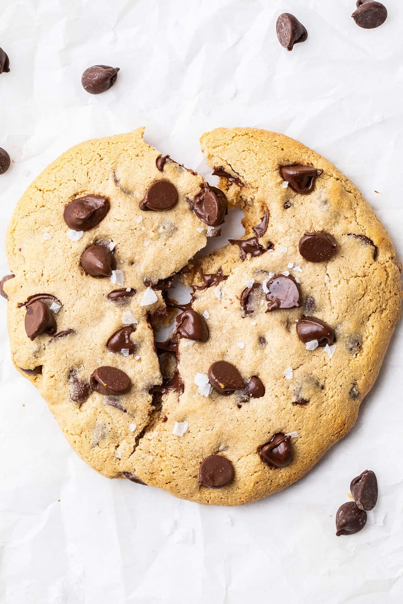 A protein cookie with chocolate chips shown broken in half with melted chocolate chips.