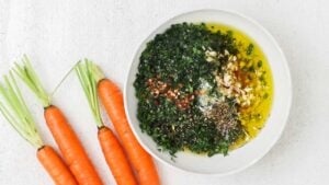 Very finely chop carrot tops, Italian parsley, and garlic. Add to a bowl.