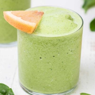 A close up look at a green smoothie garnished with a grapefruit slice.