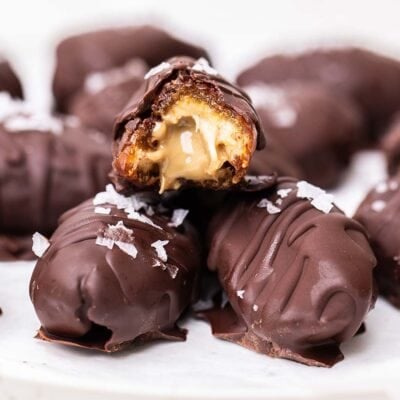 Dates covered in chocolate shown with a bite taken with a nut butter filling.
