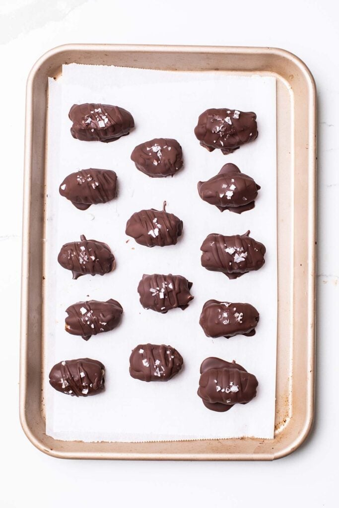 Dates shown rolled in chocolate with flaky salt sprinkled on top.