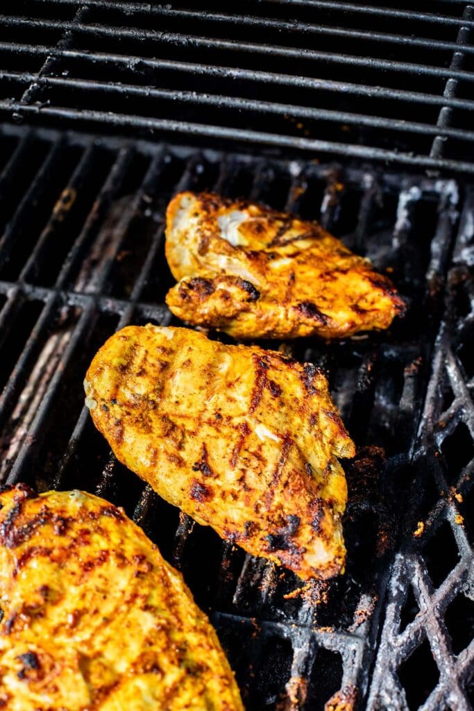 Chicken breasts cooking on a grill.