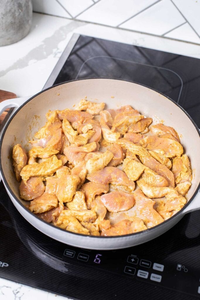 Marinated chicken browning in a skillet.